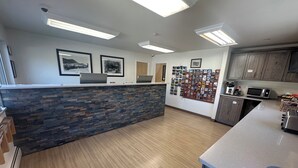 A reception area with a stone counter, framed pictures on the wall, and a bulletin board with various items. - Villa Motel at Manitou Springs (Manitou Springs)