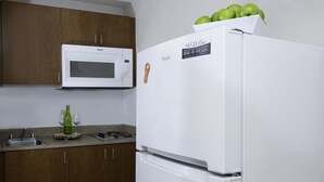 A kitchen with a white refrigerator, a microwave, and wooden cabinets. - Siegel Select Baton Rouge (Baton Rouge)