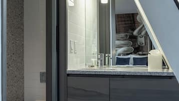 A modern bathroom with a large mirror, dark wood cabinetry, and a visible toilet.