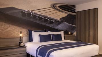 Una camera d'albergo con un letto, un comodino con un telefono, una lampada a parete e un armadio.