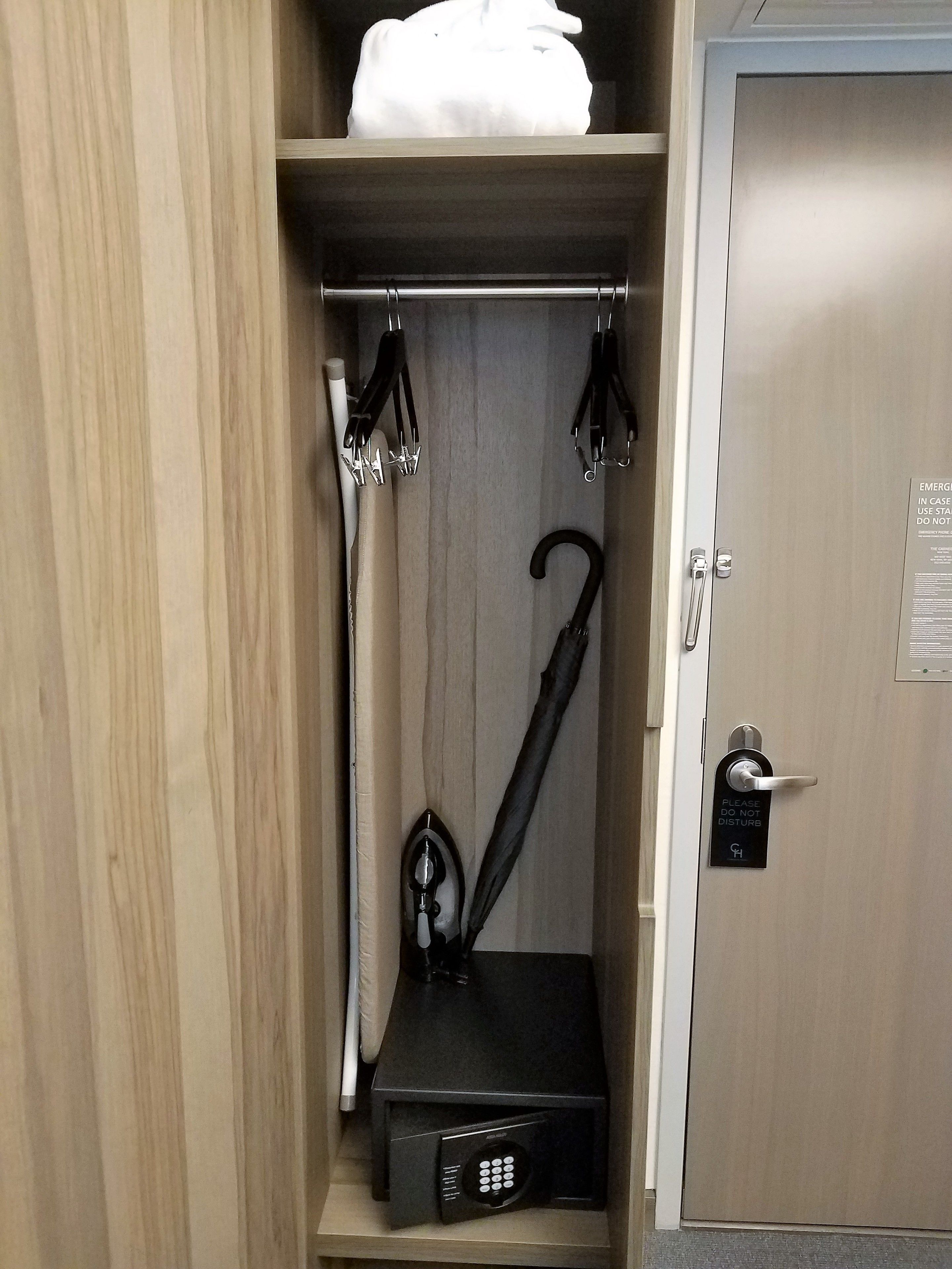 Habitación de hotel con armario de madera, minibar negro y puerta con el cartel de 'No molestar'.
