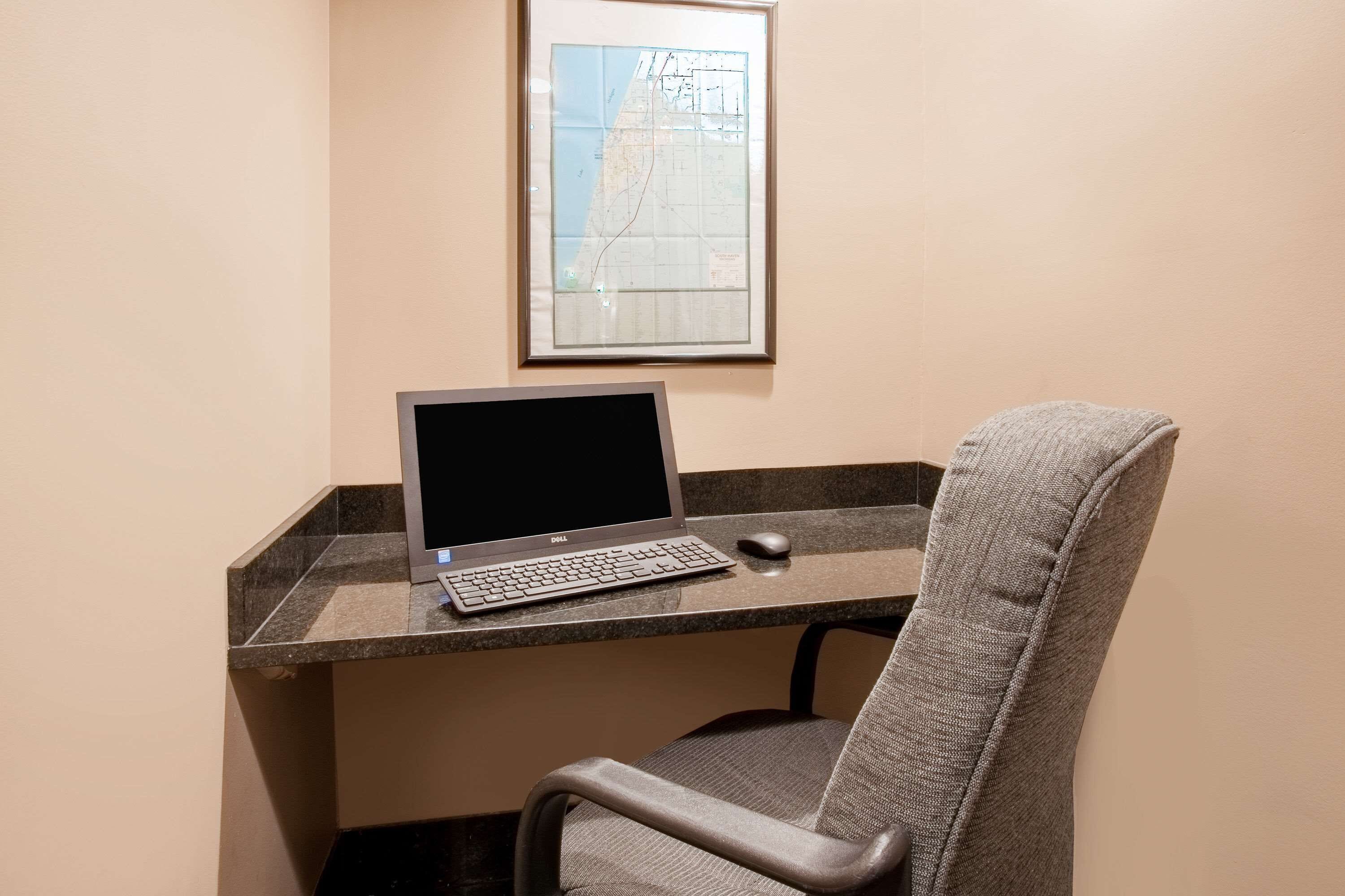 A desk with a laptop, a mouse, and a framed map on the wall.