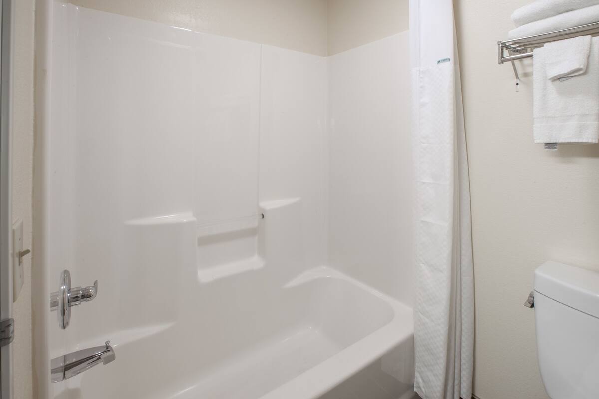 A bathroom with a white bathtub, a toilet, and a towel rack.