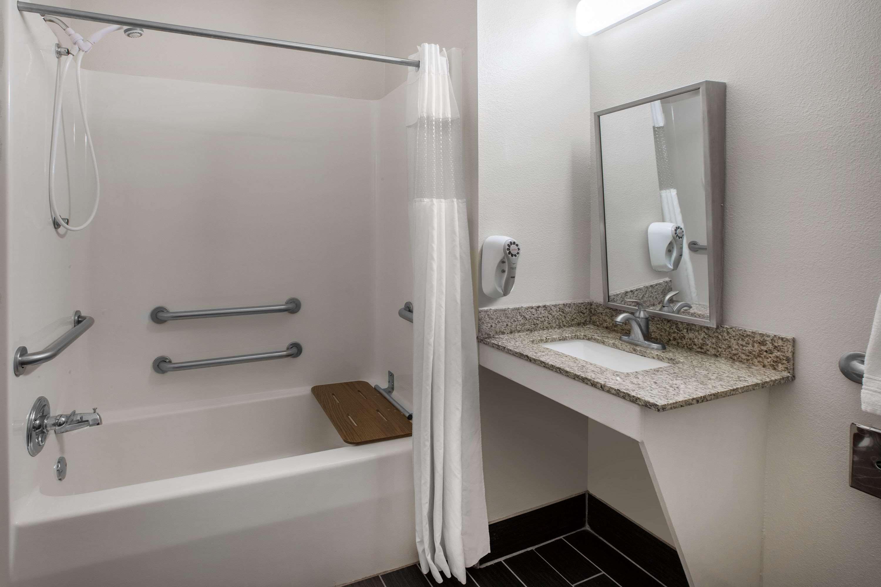 A bathroom with a bathtub, a shower, a vanity with a sink, and a mirror.