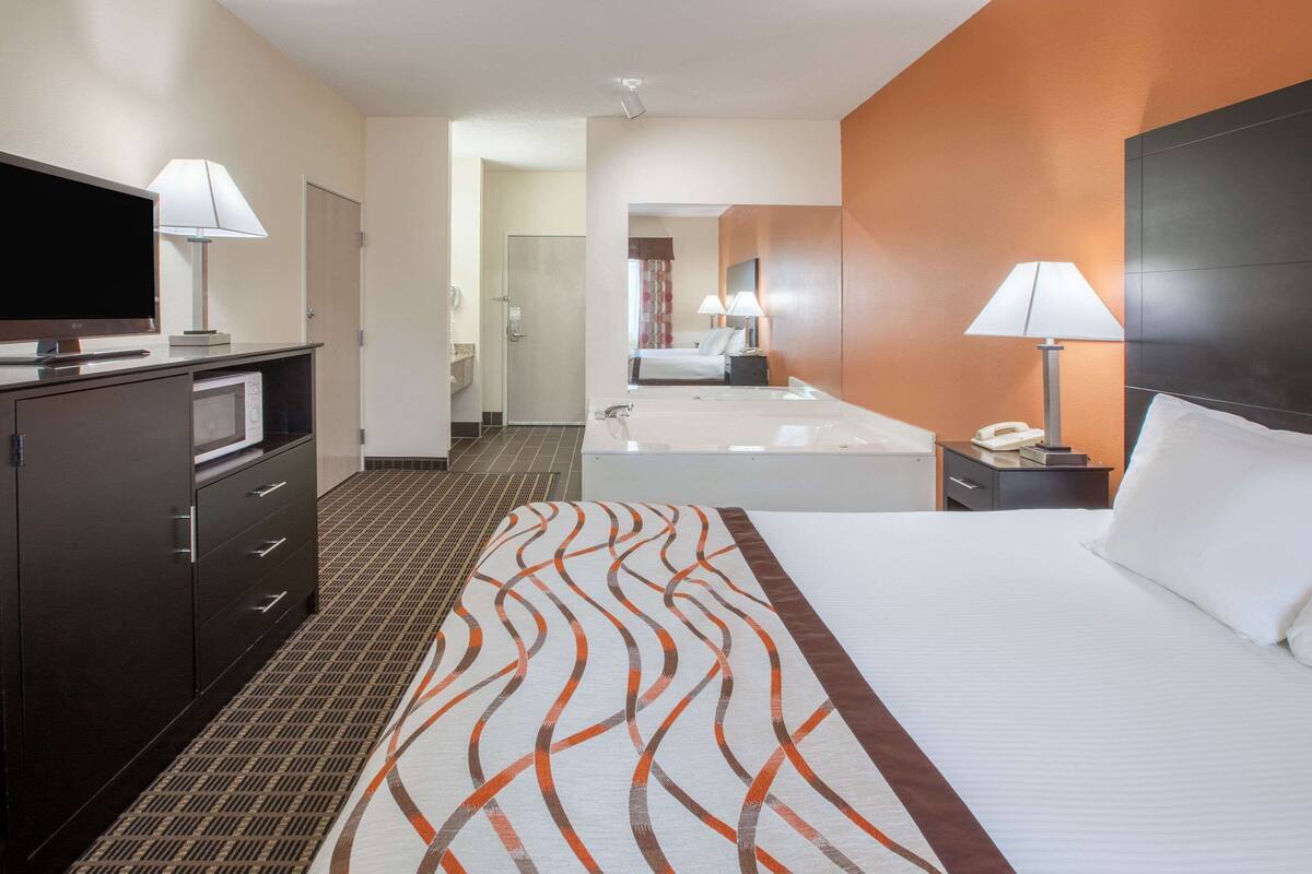 A hotel room with a bed, a TV, a desk, and a bathroom.