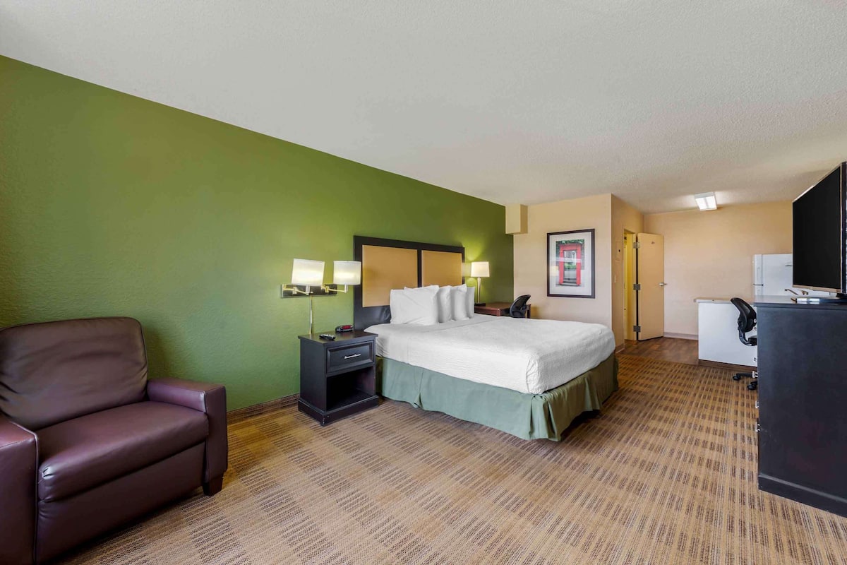 A hotel room with a bed, a desk, a chair, and a television.