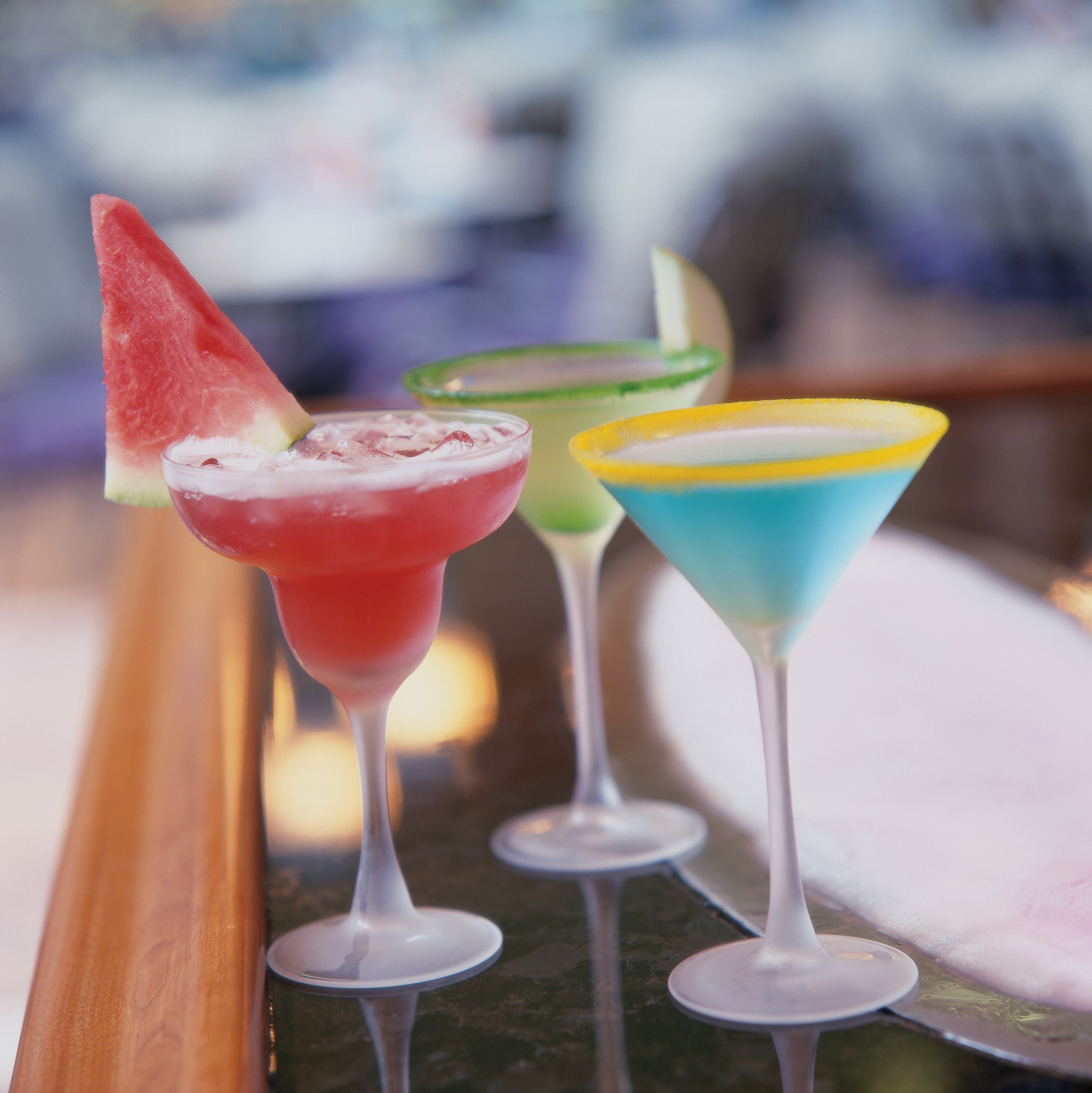 Three cocktails in martini glasses on a tray.