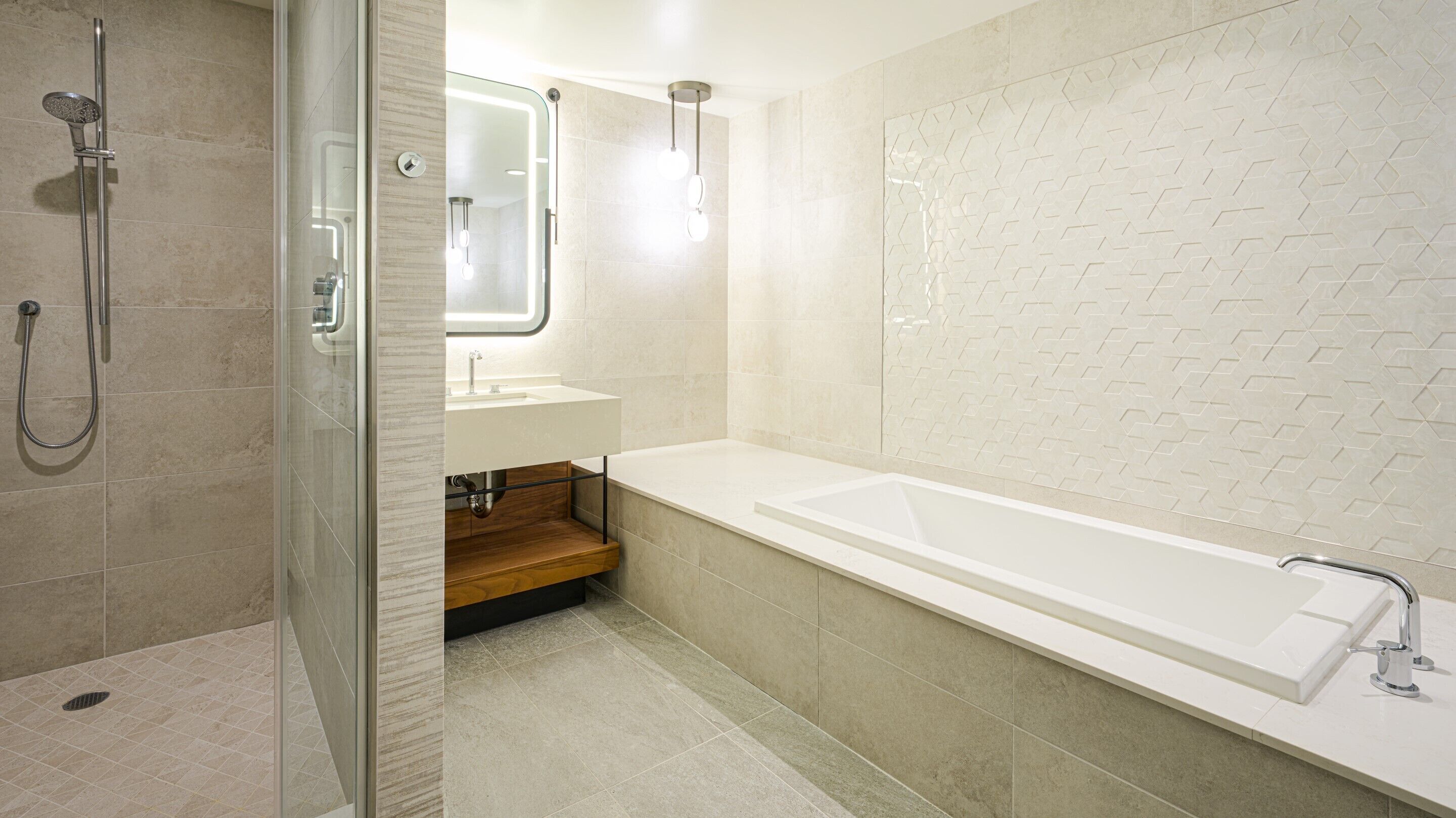 A modern bathroom with a glass-enclosed shower, a wooden vanity, and a large bathtub.
