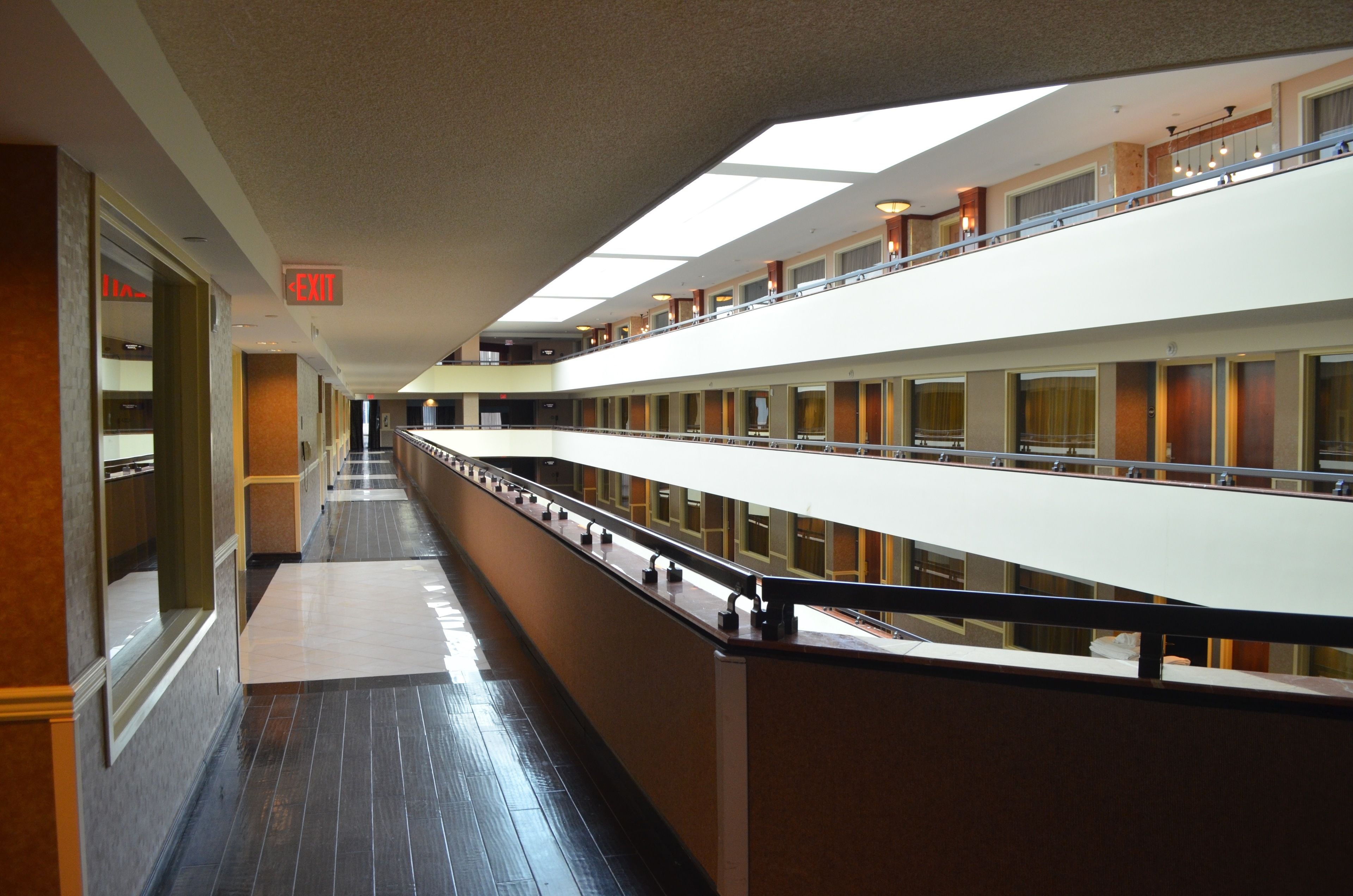 A hotel corridor with multiple floors, a central walkway, and a visible exit sign.