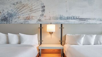 Habitación de hotel con dos camas, una mesita de noche y una lámpara de pared.