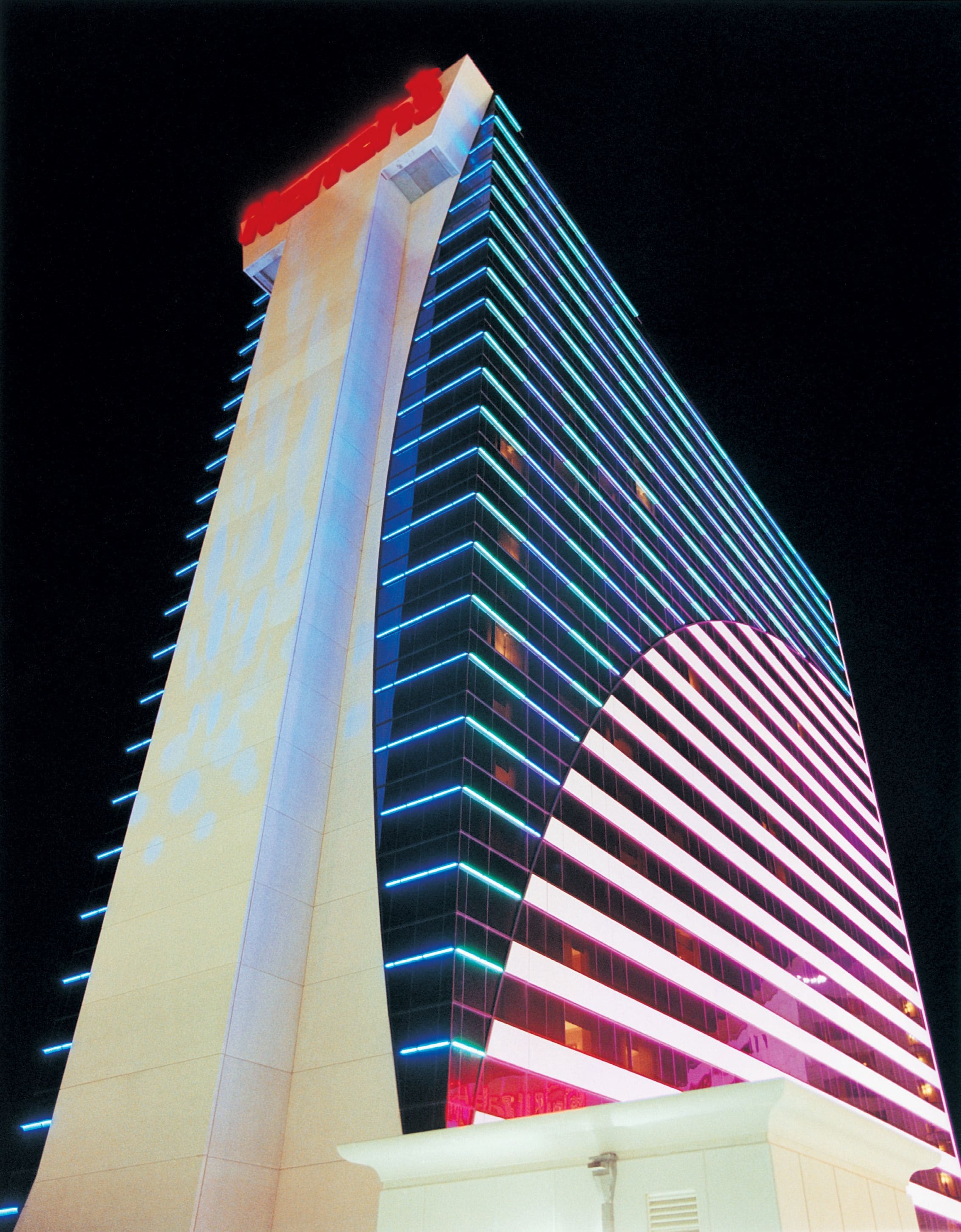 Un hotel alt amb una façana corba característica i línies de neó il·luminades.