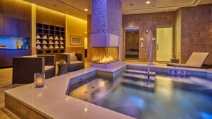 Un área de spa con piscina climatizada, asientos y chimenea empotrada.