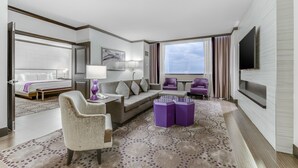 Una habitación de hotel moderna con una cama grande, un sofá, una silla, una mesita y un televisor.