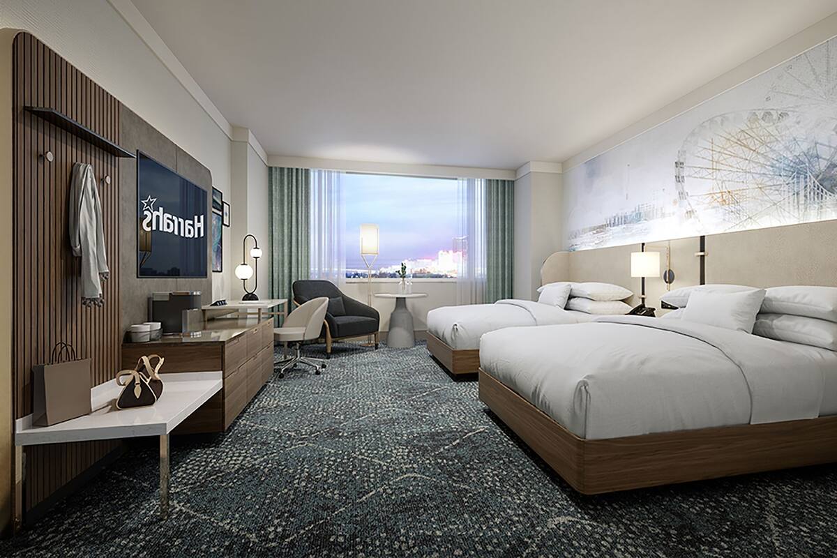 Ein Hotelzimmer mit einem großen Bett, einem Schreibtisch, einem Sessel, einem Fernseher und Blick auf die Stadt durch das Fenster.