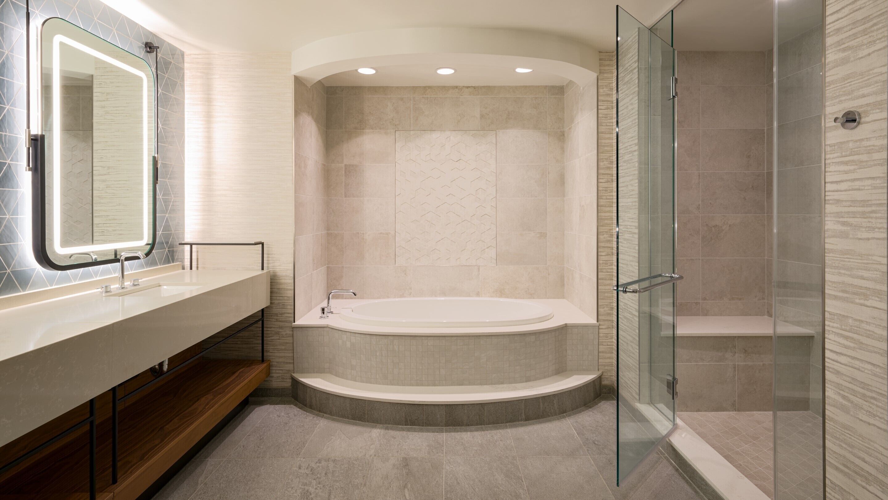 A modern bathroom with a freestanding bathtub, a glass-enclosed shower, and a vanity with a mirror.