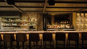 A bar area with multiple seating options and a well-stocked liquor shelf. - The Mercer (New York)