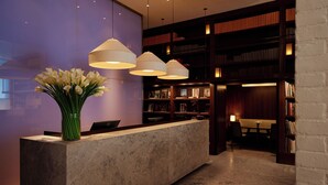 A reception area with a marble counter, a vase of flowers, and a bookshelf in the background. - The Mercer (New York)