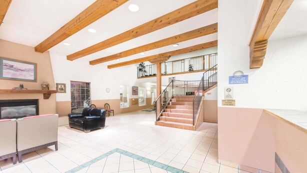 A spacious lobby with a high ceiling, wooden beams, a staircase, and a non-smoking sign. - Days Inn & Suites by Wyndham Lordsburg (Lordsburg)