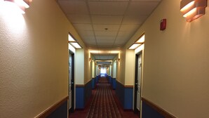 A hotel hallway with a patterned carpet, blue and beige walls, and doors on both sides. - Days Inn & Suites by Wyndham Lordsburg (Lordsburg)