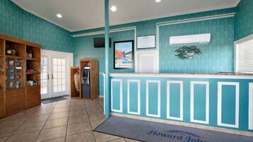 A reception area with a teal wall, a reception desk, a wooden cabinet with drawers, and a door.
