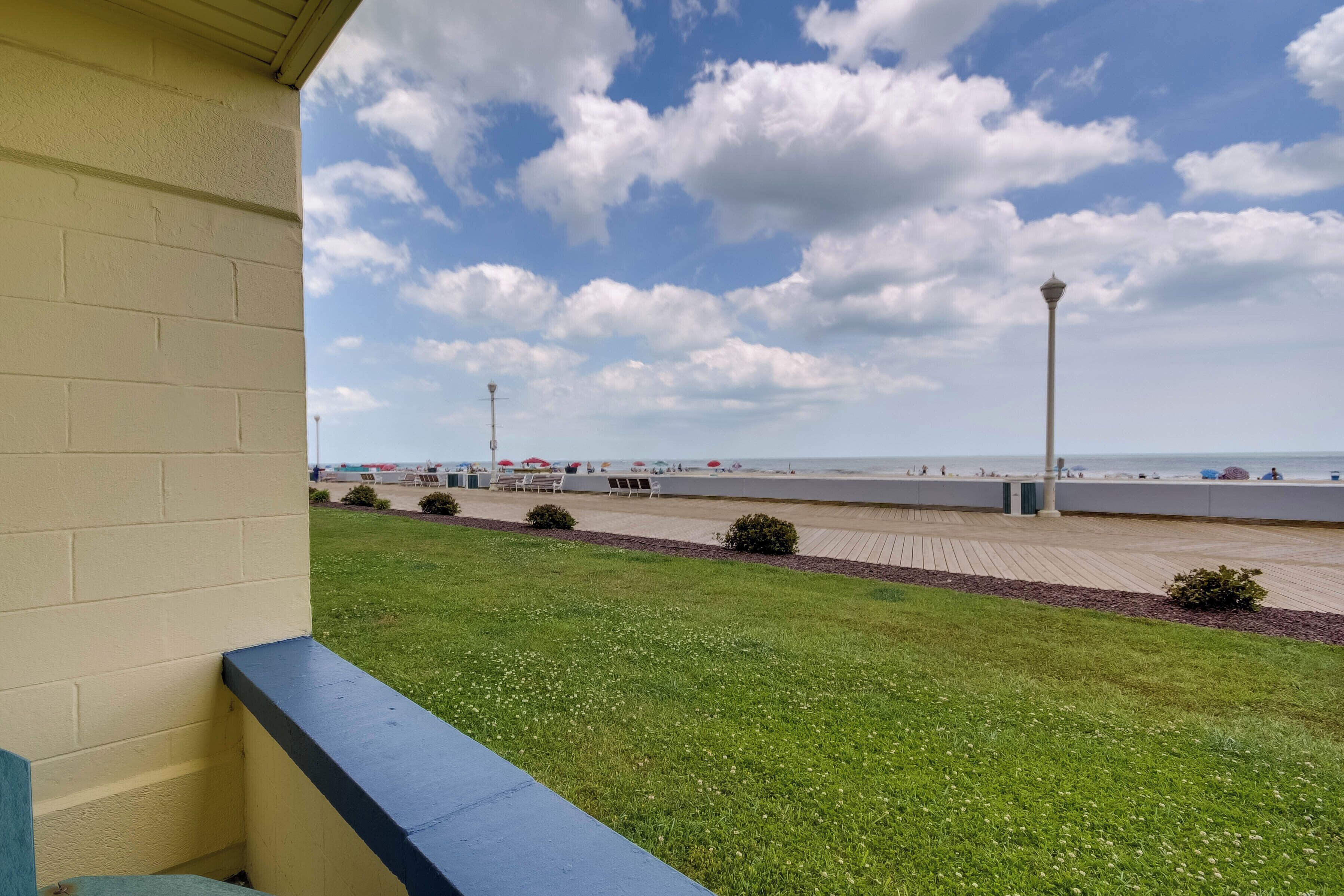 Vista di una spiaggia con un marciapiede lastricato, un lampione e una zona verde in primo piano.