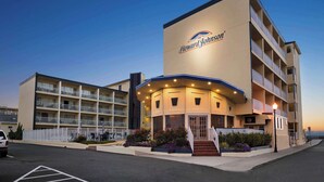 Un hotel Howard Johnson con una entrada curva, varios balcones y un estacionamiento.