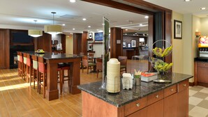 A hotel kitchen with a central island, bar seating, and a buffet area. - Hampton Inn Detroit/Auburn Hills South (Auburn Hills)