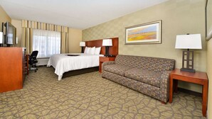 A hotel room with a bed, a sofa, a desk, a chair, and a TV. - Hampton Inn Detroit/Auburn Hills South (Auburn Hills)