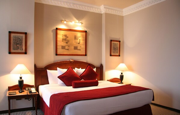 A hotel room with a large bed, two bedside tables with lamps, and framed pictures on the walls.