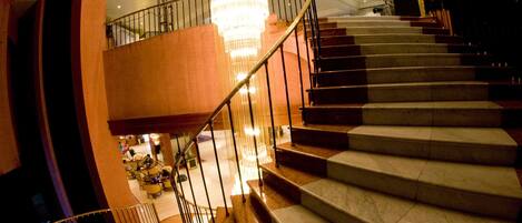 A grand staircase with marble steps and a metal railing, leading to an upper floor.