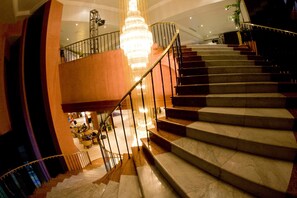 Eine prachtvolle Treppe mit Marmorstufen und Metallgeländer, die zu einer oberen Etage führt.