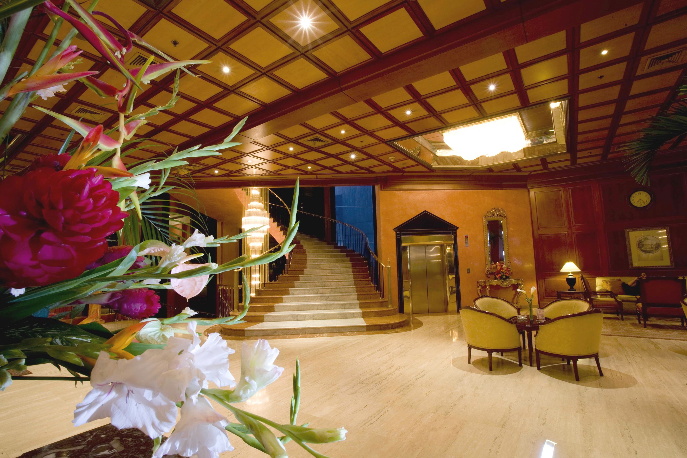 A lobby with a marble floor, a staircase, and a reception area with chairs and a desk.