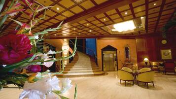 A lobby with a marble floor, a staircase, and a reception area with chairs and a desk.
