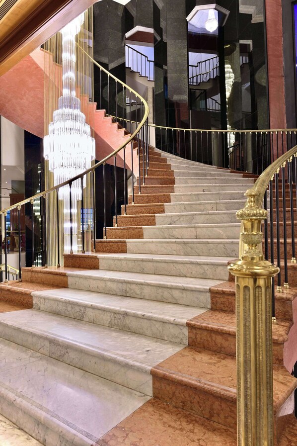 A grand staircase with marble steps and a golden handrail, leading to a high-ceilinged area with a large chandelier. - Meliá Caracas (Caracas)