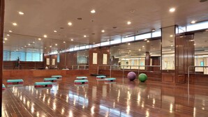 Ein geräumiges Zimmer mit Holzboden, Spiegelwänden und mehreren ausgelegten Trainingsmatten.