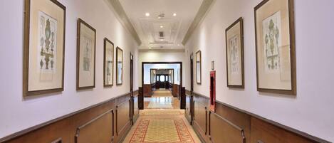 A hallway with framed artwork on the walls, a patterned carpet, and wooden paneling.