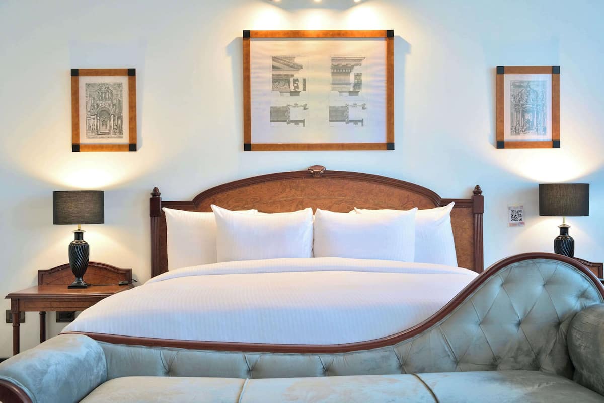 A neatly made bed with a wooden headboard, two bedside tables with lamps, and framed artwork on the walls.