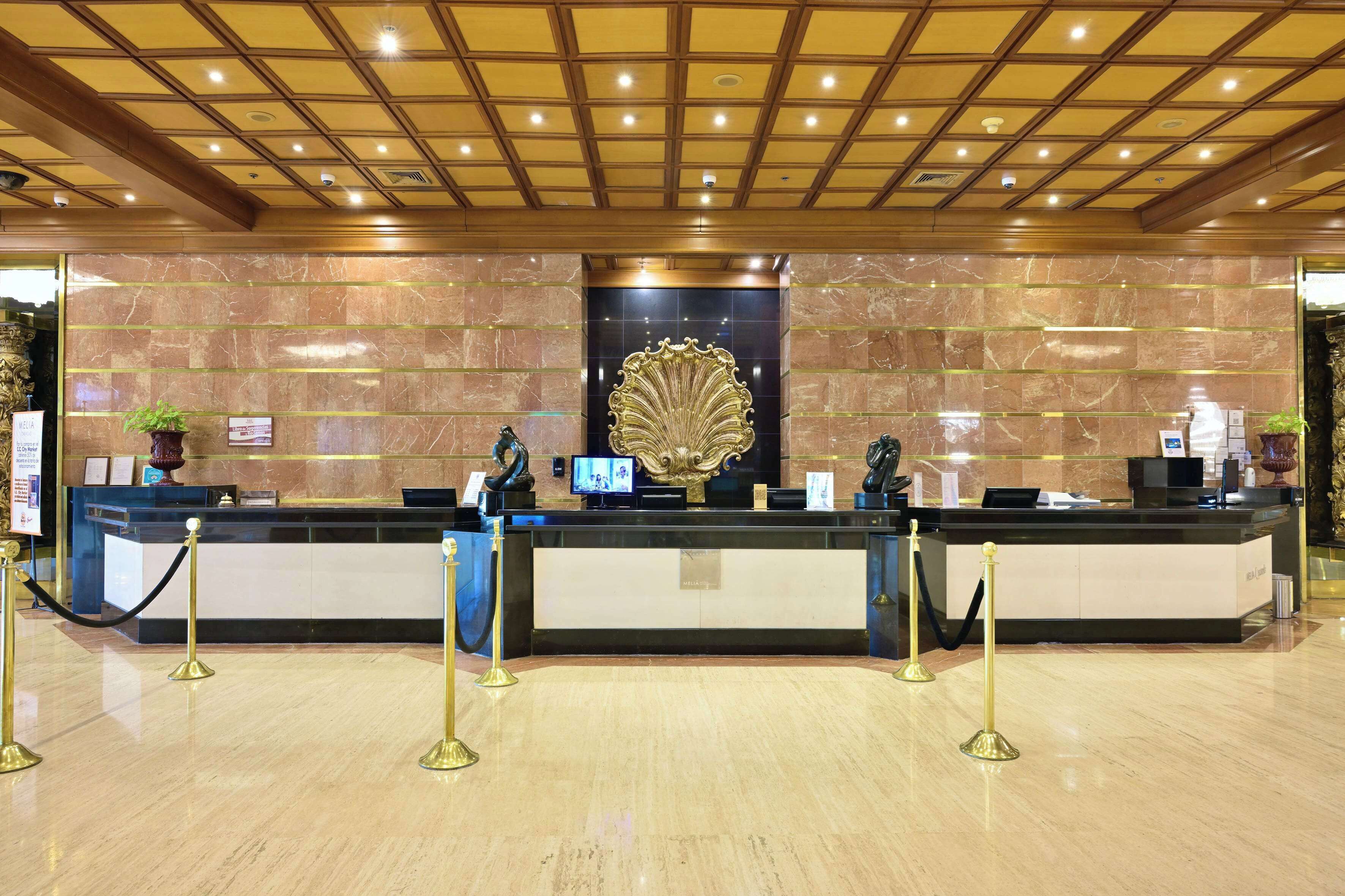A hotel reception area with marble walls, a reception desk, and a decorative golden emblem.