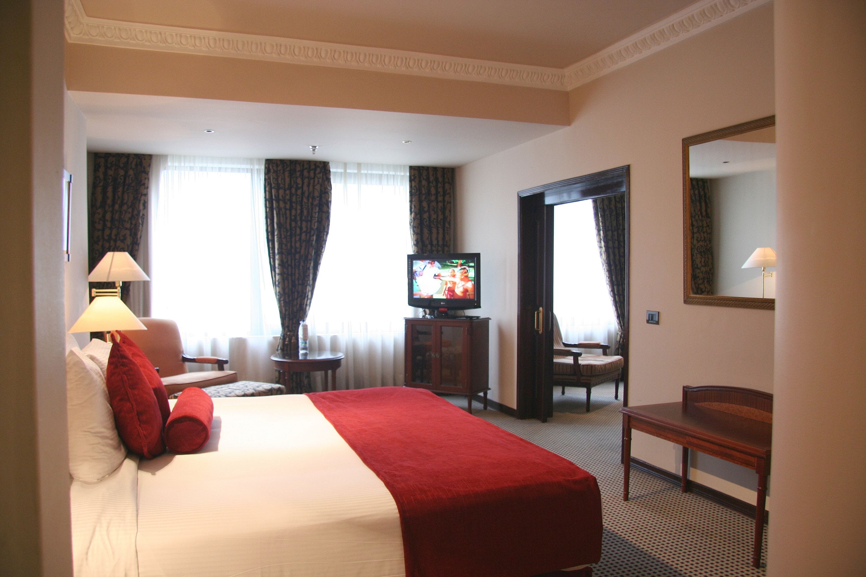A hotel room with a large bed, a television, a desk, and a chair.