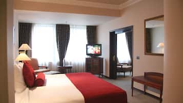 A hotel room with a large bed, a television, a desk, and a chair.