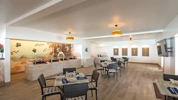 Un comedor amplio con techos altos, iluminación moderna y un gran mural de una escena de playa.