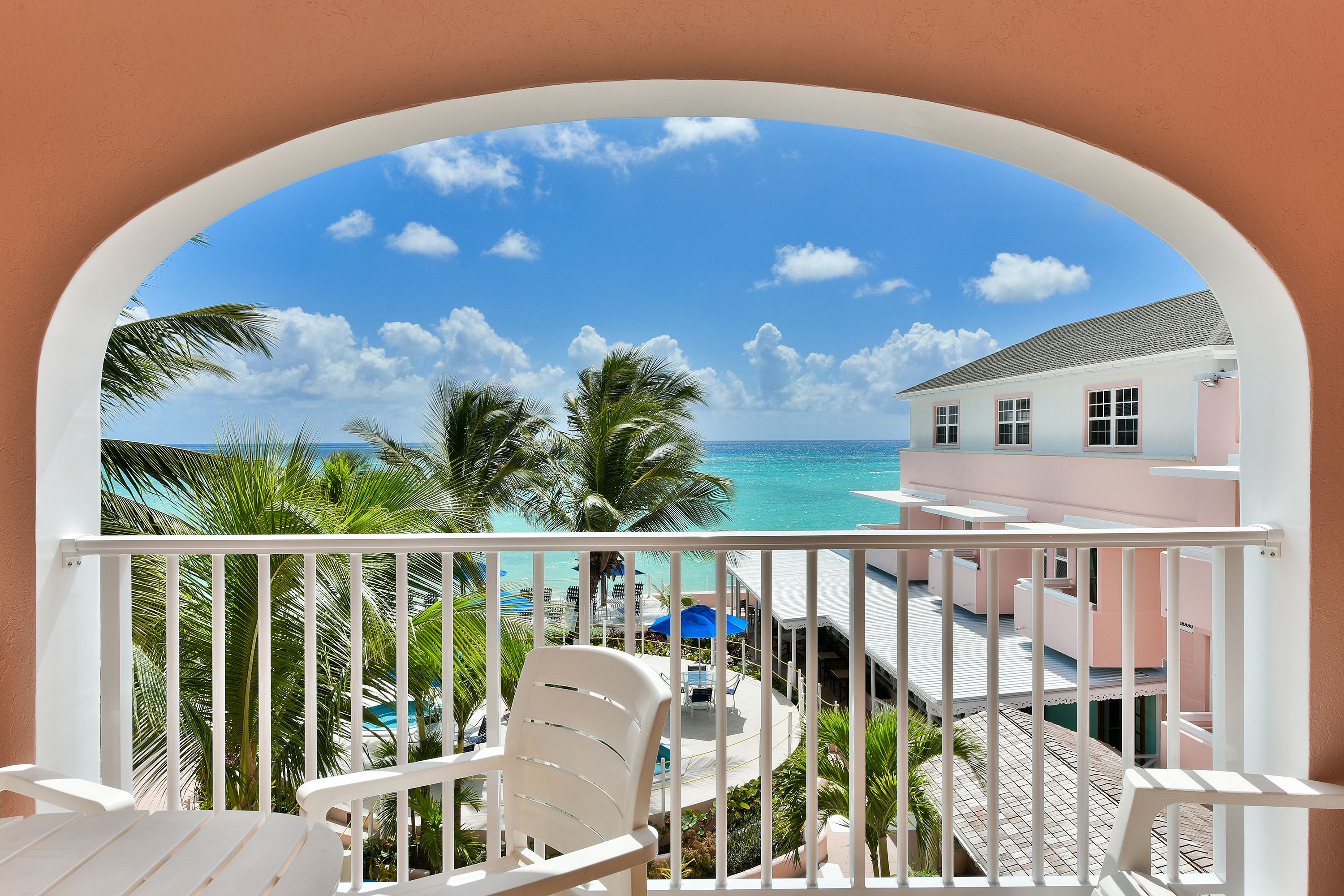 A balcony with a view of a beach and a pool area.