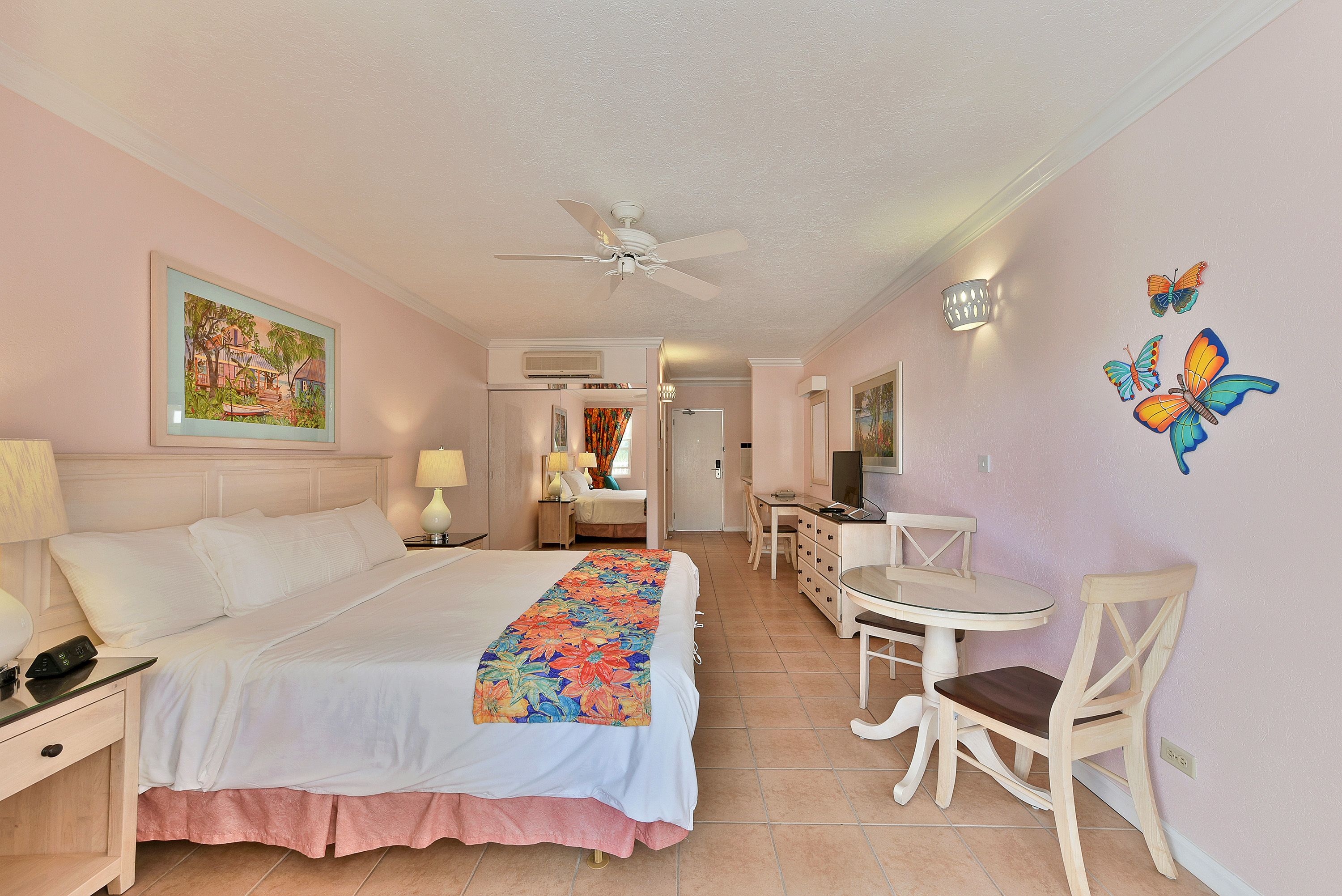 A hotel room with a bed, bedside table, lamp, and a desk with a chair.