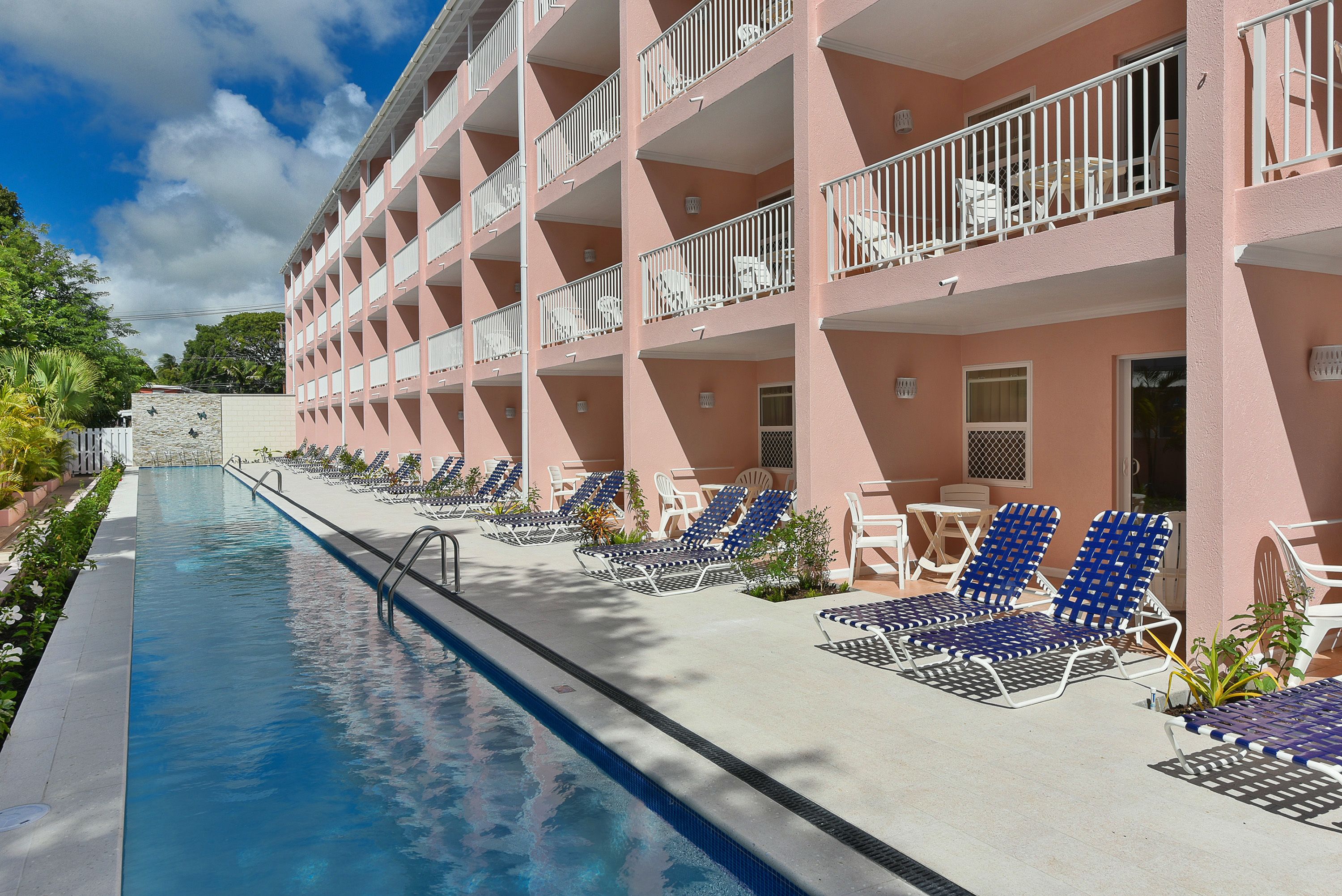 A hotel with a poolside area, multiple balconies, and lounge chairs.