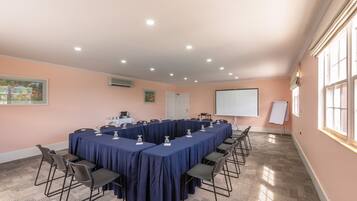 A conference room with a long table, chairs, a projector screen, and a whiteboard.