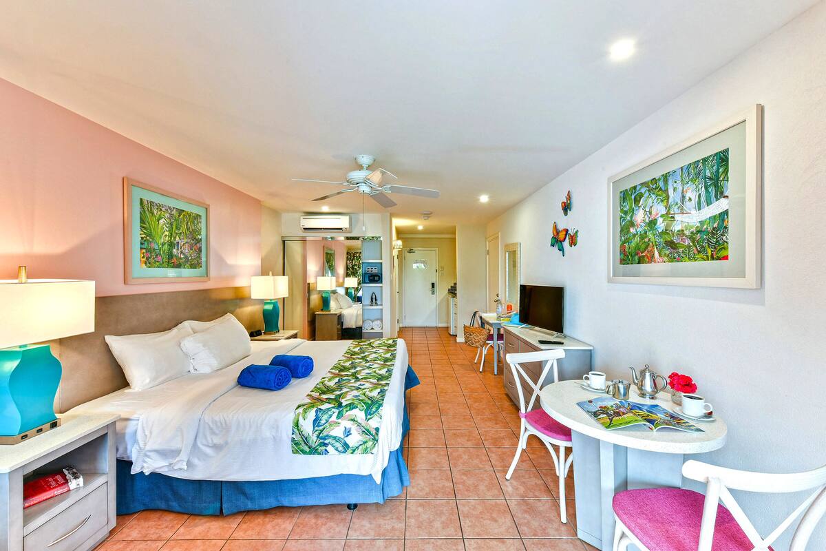 A hotel room with a bed, desk, chair, and artwork on the walls.