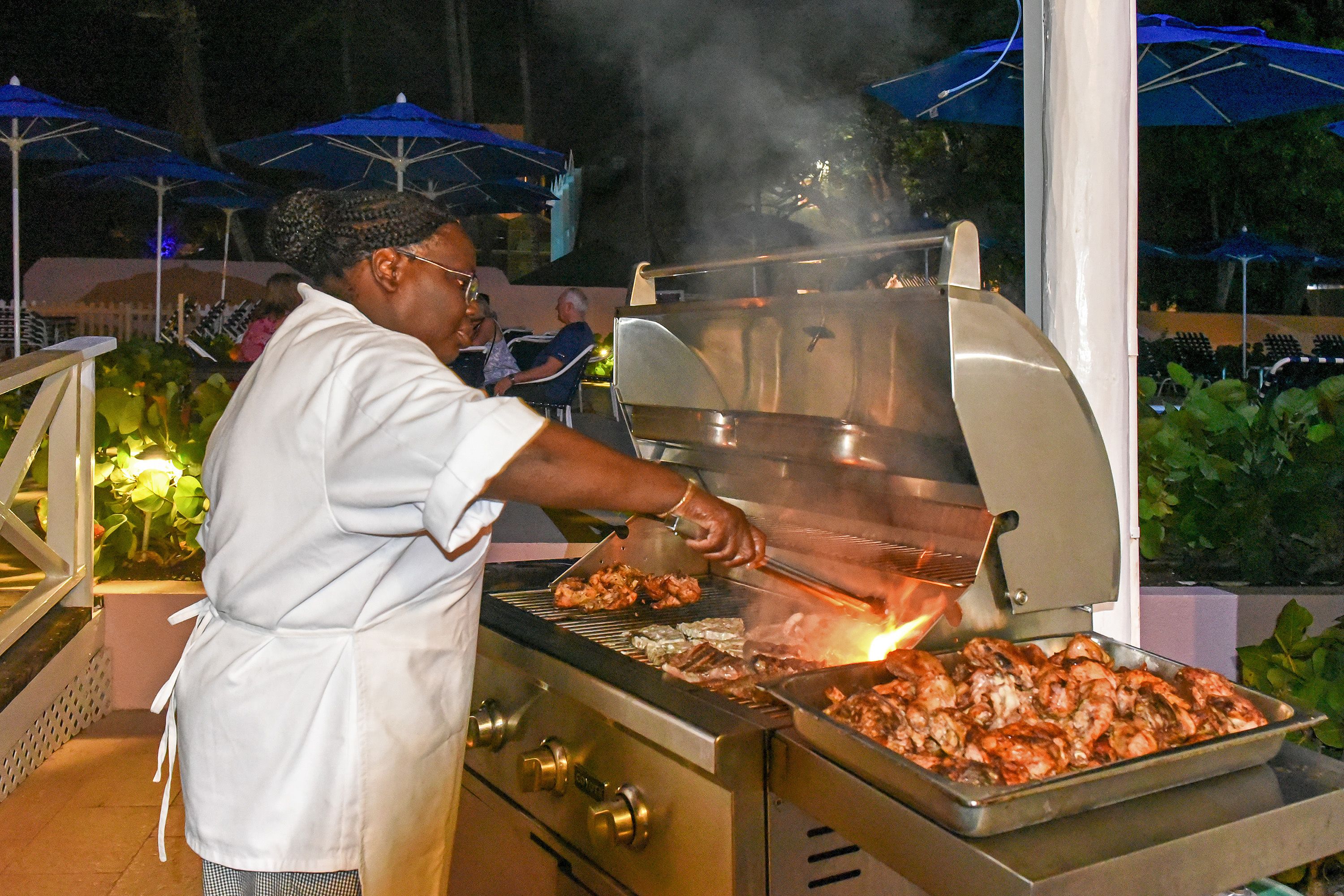 Un cocinero asando alimentos al aire libre de noche.
