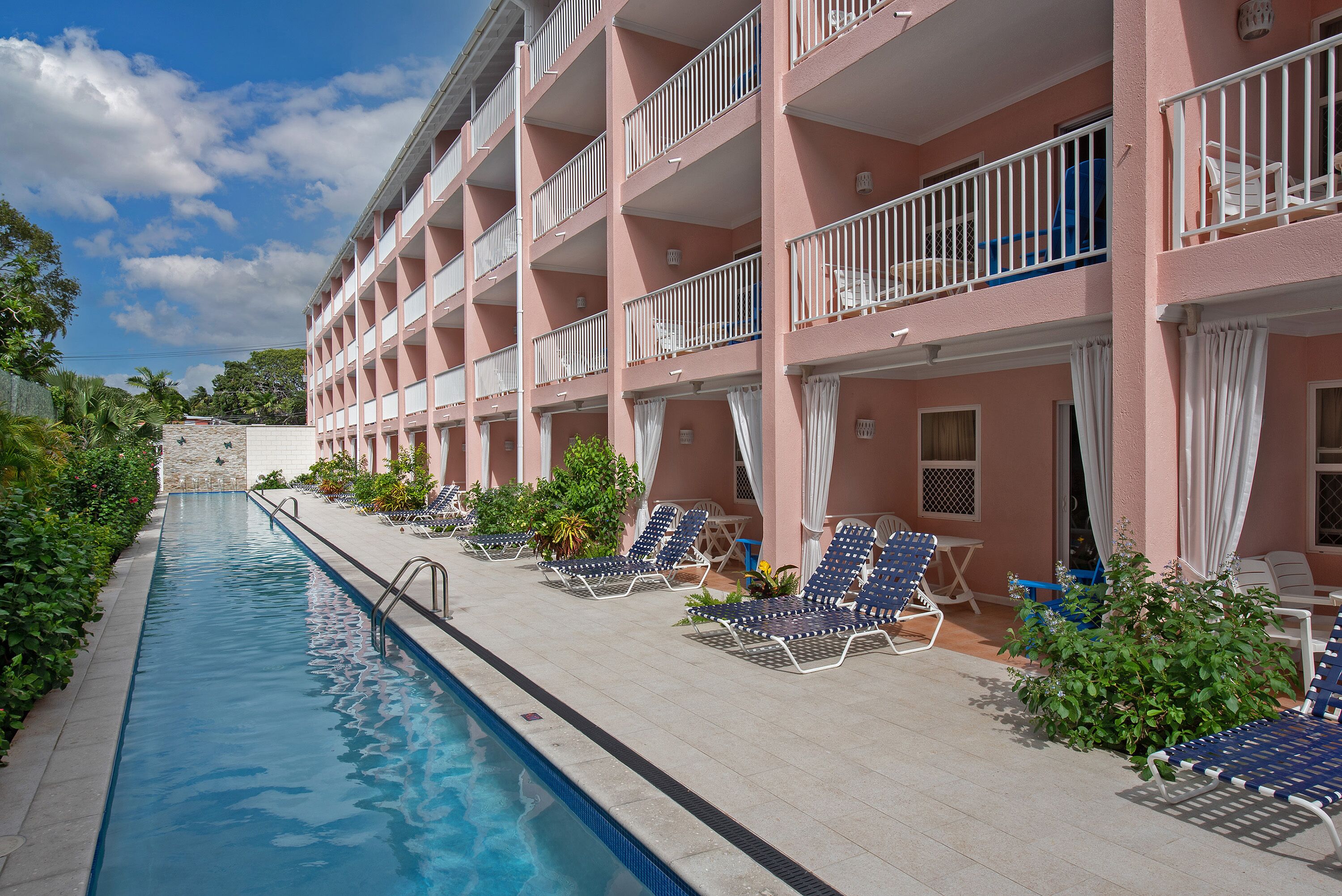 Un hotel con piscina, sillones de descanso y balcones.