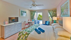 A hotel room with a bed, a TV, a desk, and a balcony. - Butterfly Beach Hotel (Oistins)