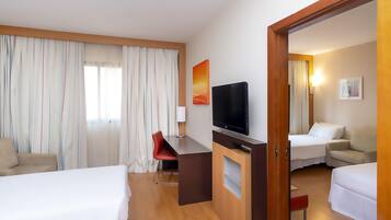 A hotel room with a bed, a desk with a TV, a chair, and a mirror.